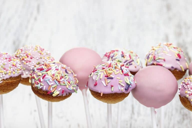 Pink cake pops on white wooden background. Copy space