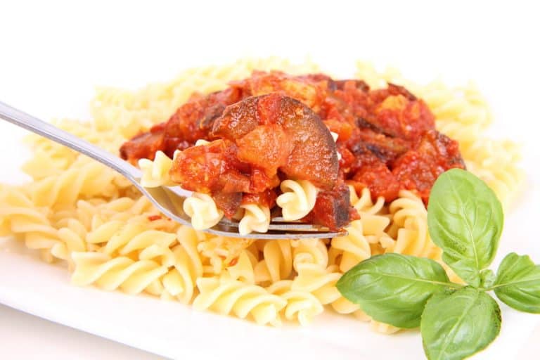 Fusilli pasta with pork & eggplant sauce, being eaten with a fork